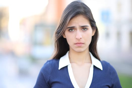Sad woman looking at camera standing in the street