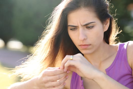 Worried fiancee looking at engagement ring in a park