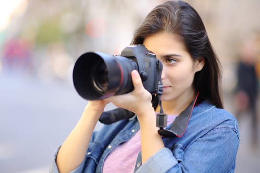 Serious photographer taking picture with dslr professional camera in the street