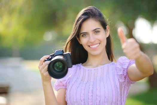 Front view portrait of a happy photographer gesturing thumbs up