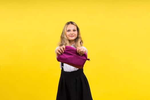 Little teenager girl with pencil case on a yellow background