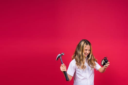 Kid girl holding hammer and alarm clock smiling with happy and cool smile on face. showing teeth.