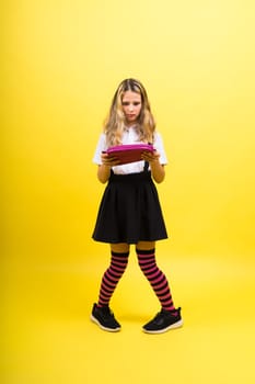 Little teenager girl with pencil case on a yellow background
