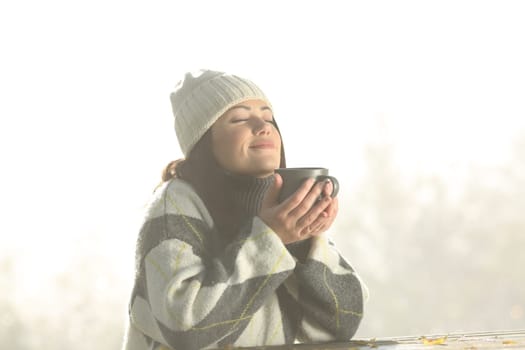 Woman in winter in a park smelling coffee and breathing fresh air