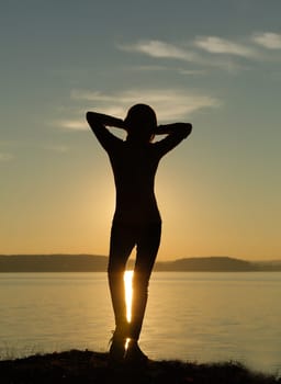 A serene silhouette of a person relaxing at sunset by a tranquil lake, enjoying the peaceful evening scenery