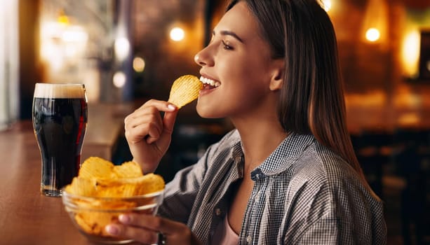 gorgeous young woman eating crisps drinking beer at the pub, AI generated image
