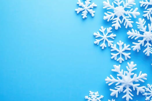 Delicate white snowflakes are artistically arranged on a clean blue background, creating a cheerful winter ambiance. Perfect for celebrating a festive season filled with joy and creativity.