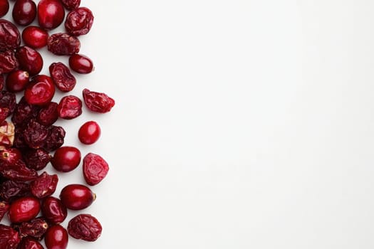 A variety of dried cranberries in rich red hues are arranged on a clean, solid white surface, highlighting their texture and color, perfect for healthy snacking or baking options.