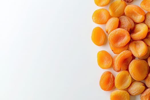 A collection of dried apricots rests on a pristine white surface, showcasing their vibrant orange color and smooth texture.