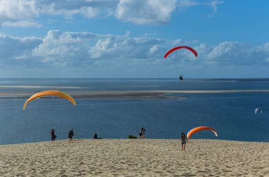 Dune of Pilat, France - August 14, 2024: People paragliding at the Great Dune of Pilat, Arcachon Basin, Nouvelle Aquitaine, France.