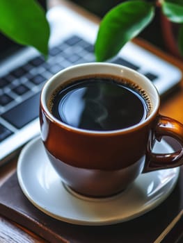 Steaming cup of coffee on laptop keyboard with green plant leaves in background, symbolizing work life balance and productivity in a home office setting.