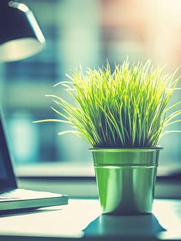 Vibrant green ornamental grass in a stylish pot sits on an office desk, adding a touch of nature to the workspace with a desk lamp in the background.