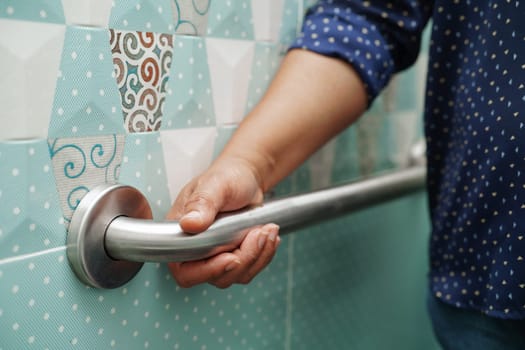 Asian woman use toilet support rail in bathroom, handrail safety grab bar, security in nursing hospital.