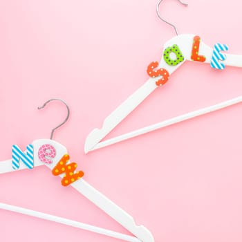 Creative top view flat lay white wooden hangers sale text pastel pink background copy space minimalism style. Template fashion feminine social media sale children store promo design shopping concept