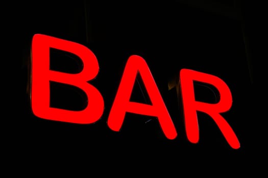 bright red neon sign advertising a bar in a German city center at night