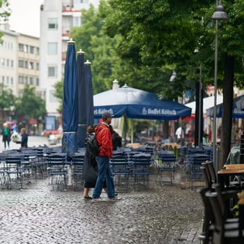 Tourists in the rain in front of a restaurant in the city center of Cologne in Germany