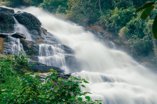 Beautiful waterfall with a lush green forest in the background. The water is flowing down the rocks and creating a beautiful scene. Sustainable waterfall in lush forest promoting water sustainability.