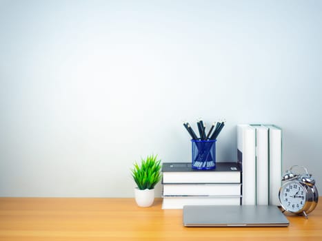 Workspace mock up white table top with laptop, Pencils, Book, Alarm clock and green houseplant. Copy space desk with copy space for products display montage. Minimalist white workplace with supplies.