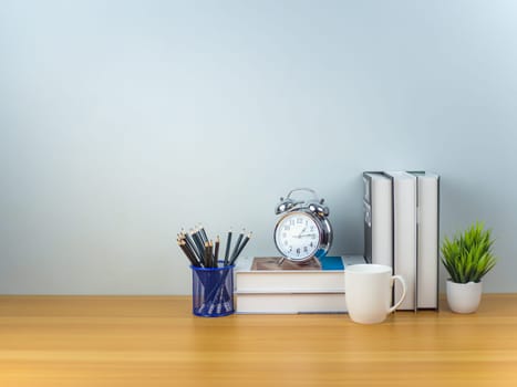 Workspace mock up white table top with Coffee cup, Pencils, Book, Alarm clock and green houseplant,Copy space desk with copy space for products display montage, Minimalist workplace with supplies.