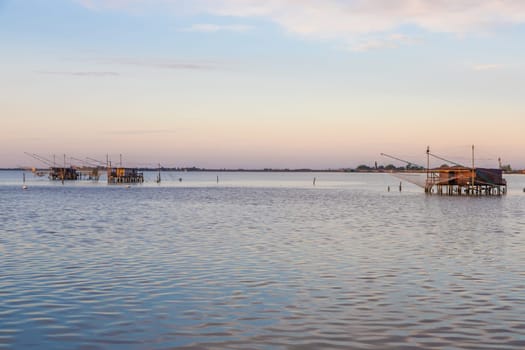 Italy, Comacchio lagoon. Panorama with traditional house for fishing at sunset