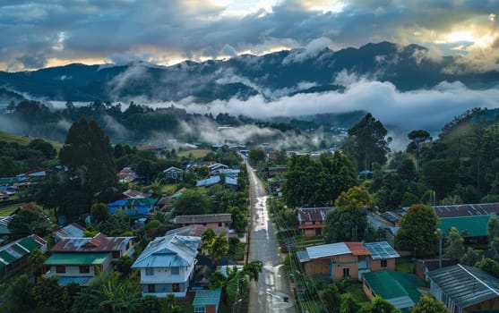 Overhead view of a serene mountain town enveloped in mist, with lush greenery surrounding cozy homes along a peaceful street at dawn