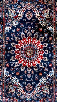 This Persian rug features a bold red central motif complemented by a deep blue background and elaborate borders