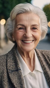 Sophisticated smiling older French woman in the open air. Demeanor reveals a lifetime of experiences and reflections, embodying grace and wisdom. Well-groomed woman 70 years old with grey hair. AI.
