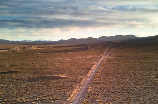 Dirt road across the desert steppes by the Andes mountains near Uspallata, Argentina.