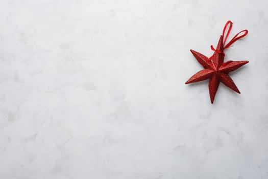 A shiny red star ornament rests elegantly on a smooth white marble surface adding a festive touch to the scene during the holiday season.