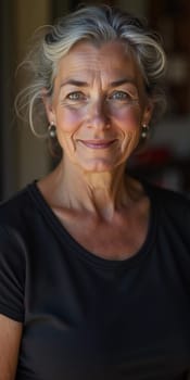 A French woman 60 years old with silver hair and a warm smile stands in her home, radiating tranquility and confidence while dressed casually in a black shirt. Generative AI.
