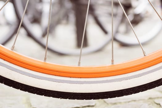 Antwerp, Belgium, October 20th 2024: close-up of a bicycle wheel with an orange rim and white tire, showing spokes