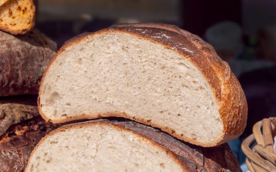 A slice of bread is cut in half, revealing the inside of the loaf. The bread has a slightly brown crust. Concept of simplicity and naturalness