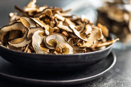 Dried porcini mushrooms. Sliced boletus on plate on a black table.