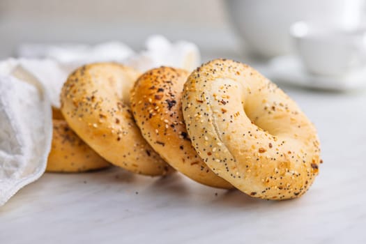 Bagel sprinkled with fried onion, sesame and poppy seeds on a kitchen table.