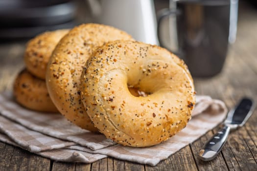 Bagel sprinkled with fried onion, sesame and poppy seeds on a wooden table.