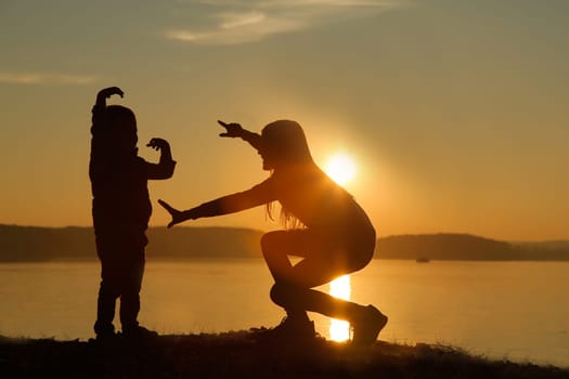 A beautiful silhouette of a girl and a child at sunset on the seashore, capturing joy and tranquility