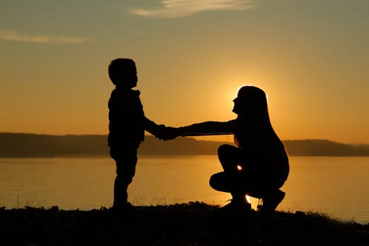 Stunning and beautiful silhouette of children joyfully holding hands against the sunset background