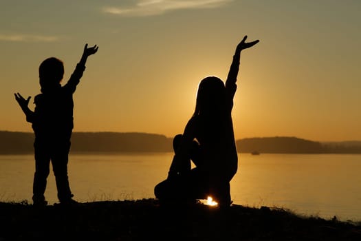 A joyful family silhouette can be seen against a stunningly beautiful sunset view over the tranquil water