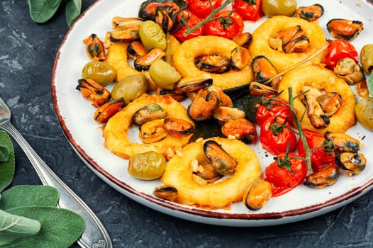 Delicious baked mussels and squid rings with sage. Exotic seafood platter.