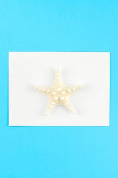 Creative flat lay concept of summer travel vacations. Top view of seashells and starfish on turquoise blue background with postcard mock up and copy space in minimal style, template for text