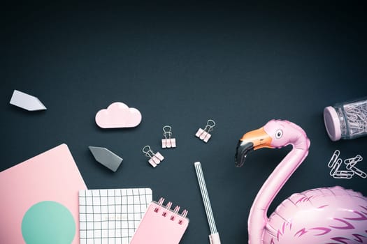 Top view flat lay feminine desk workspace styled pink colored objects design office supplies with copy space on black background. Template for blog social media