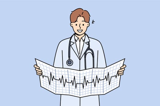 Man cardiologist holds result of ecg analysis and smiles, standing in white coat with stethoscope around neck. Cardiologist looks for symptoms of disease by observing rhythm of patient heartbeat