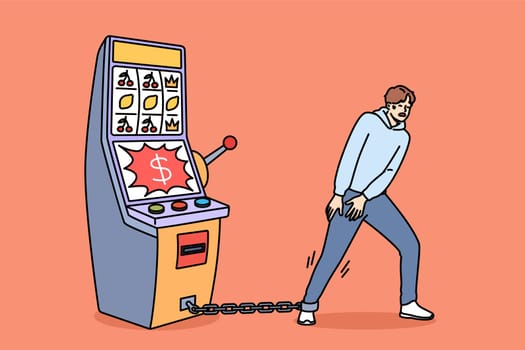 Gambling addiction of man tied with chain to slot machine made guy hostage to casino. Unhappy young human suffers from digital addiction and cannot free himself from passions to excitement