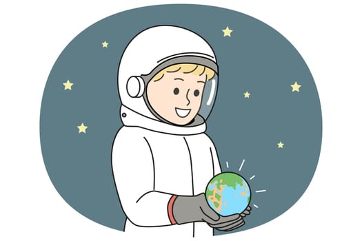 Boy dressed as astronaut is holding miniature planet earth, located in space with starry sky. Small child dreams of becoming astronaut and going on cosmos research expedition on shuttle
