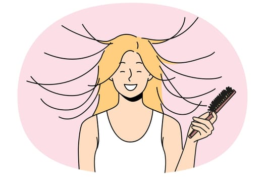 Woman combs hair and smiles, seeing effect of static magnetization of hairstyle. Funny young blonde girl takes care of own hair getting ready for date and laughing feeling surge of positive emotions