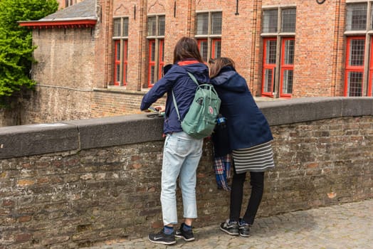 BELGIUM, BRUGES - MAY 22: Women is taking pictures on the street of Bruges on May 22, 2015