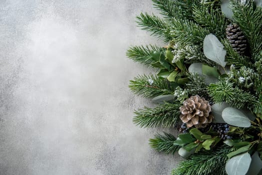 A vibrant festive wreath adorned with pinecones and assorted greenery rests against a clean solid background, perfect for holiday decorations and seasonal celebrations during winter.