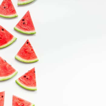 Creative scandinavian style flat lay top view of fresh watermelon slices on white table background copy space. Minimal summer fruits pattern for blog or recipe book