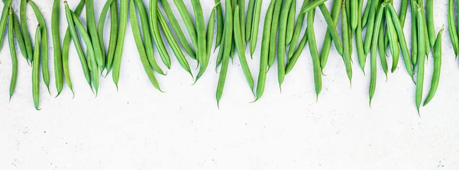 Creative scandinavian style flat lay top view of fresh green beans on white concrete table background copy space. Minimal house cooking concept template for blog or recipe book