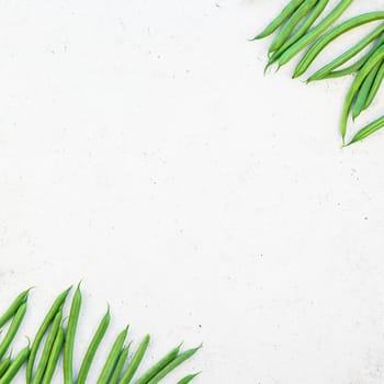 Creative scandinavian style flat lay top view of fresh green beans on white concrete table background copy space. Minimal house cooking concept template for blog or recipe book
